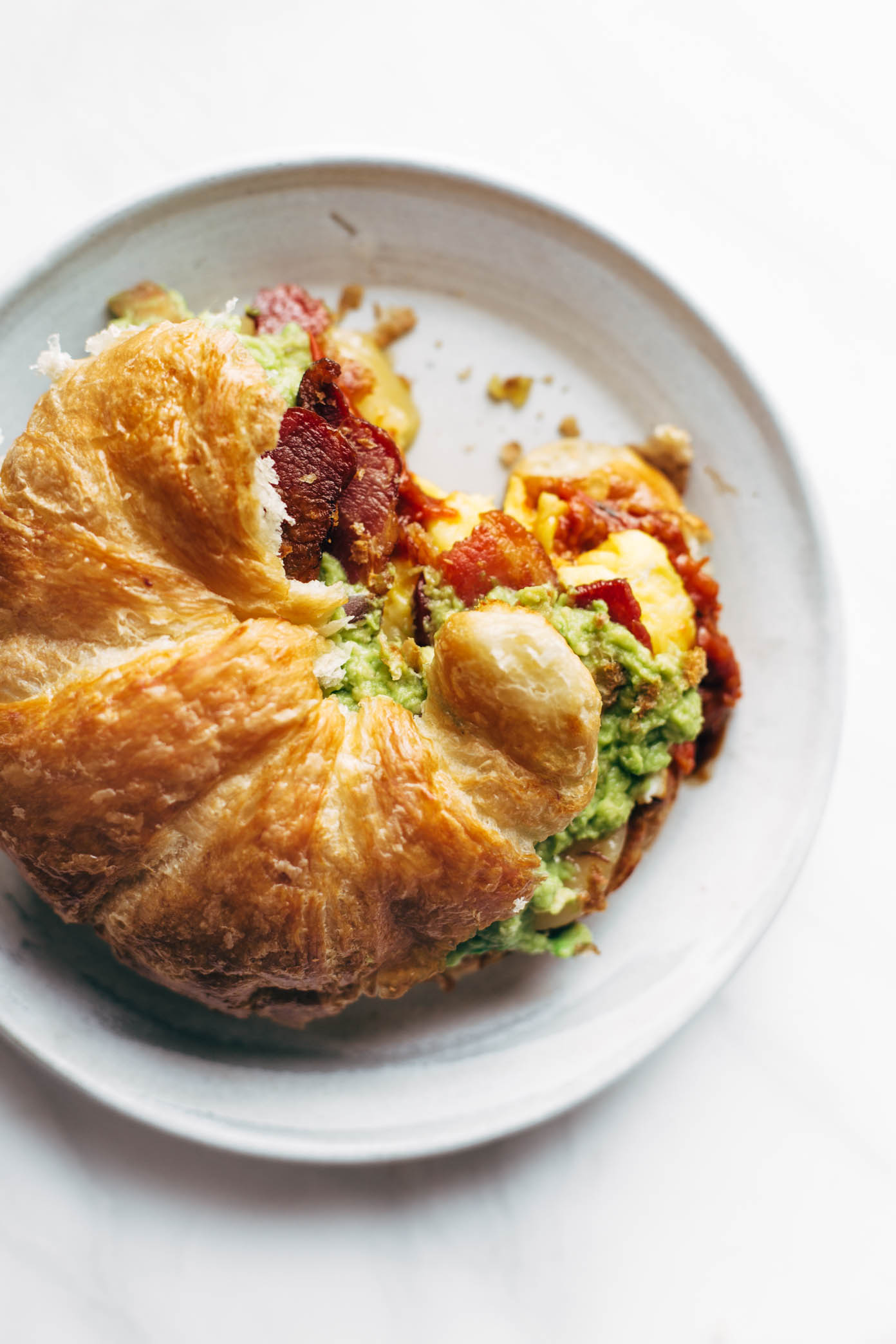 The Ultimate Breakfast Sandwich with eggs, bacon, guacamole, chunky tomato sauce, pepper jack cheese, all on a toasted croissant. ? Favorite ever. | pinchofyum.com
